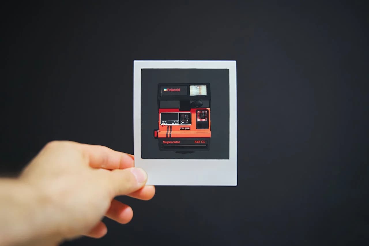 Ruka koja drži manju fotografiju polaroidnog fotoaparata