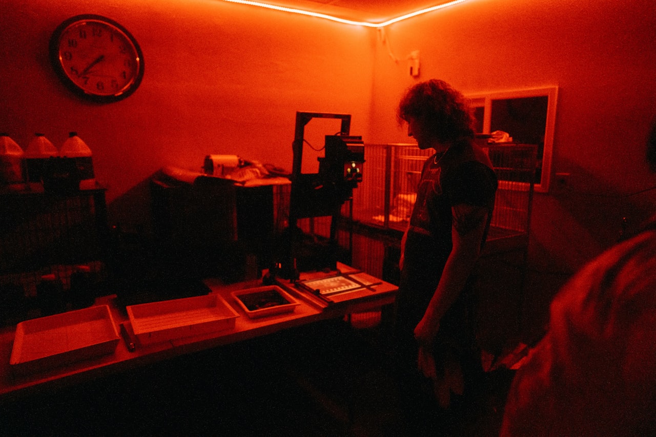 Fotograf u tamnoj sobi pod crvenim svjetlom tijekom obrade fotografije