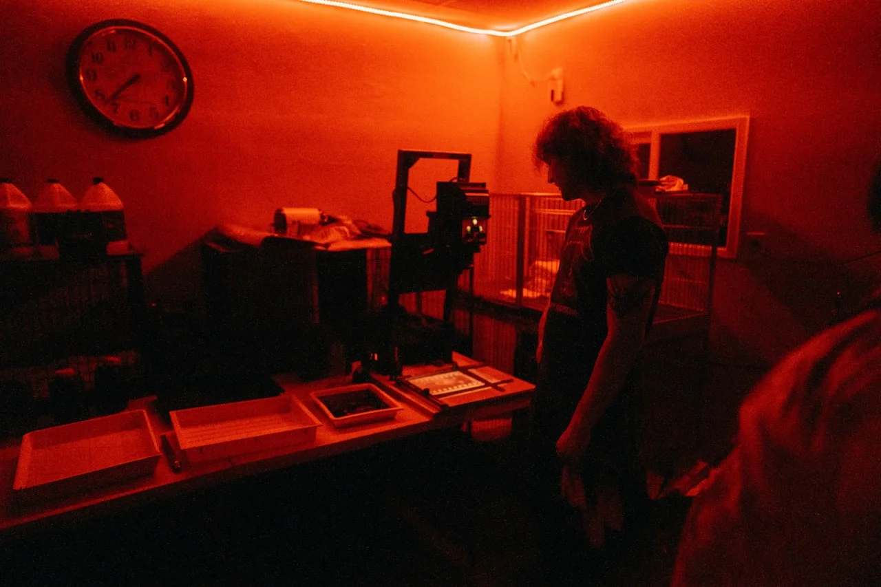 Fotograf u tamnoj sobi pod crvenim svjetlom tijekom obrade fotografije