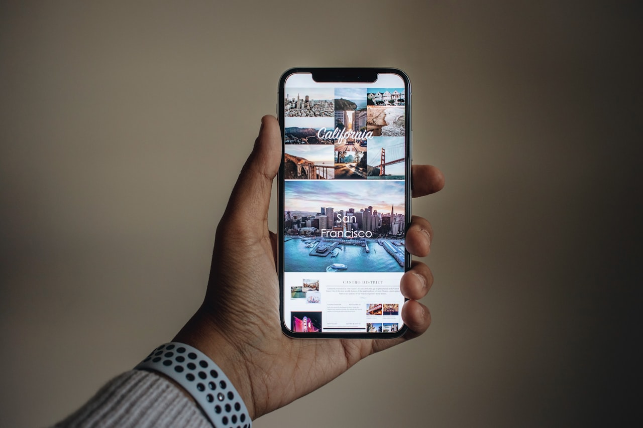 Ruka koja drži pametni telefon iznad stola s fotografijama