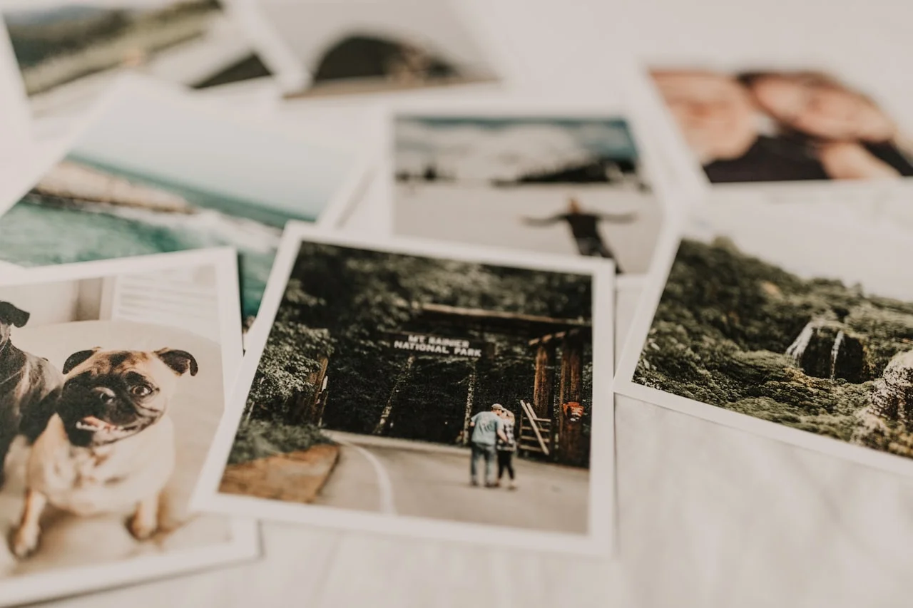 Otisnute fotografije s bijelim rubom, razmještene po svijetloj podlozi