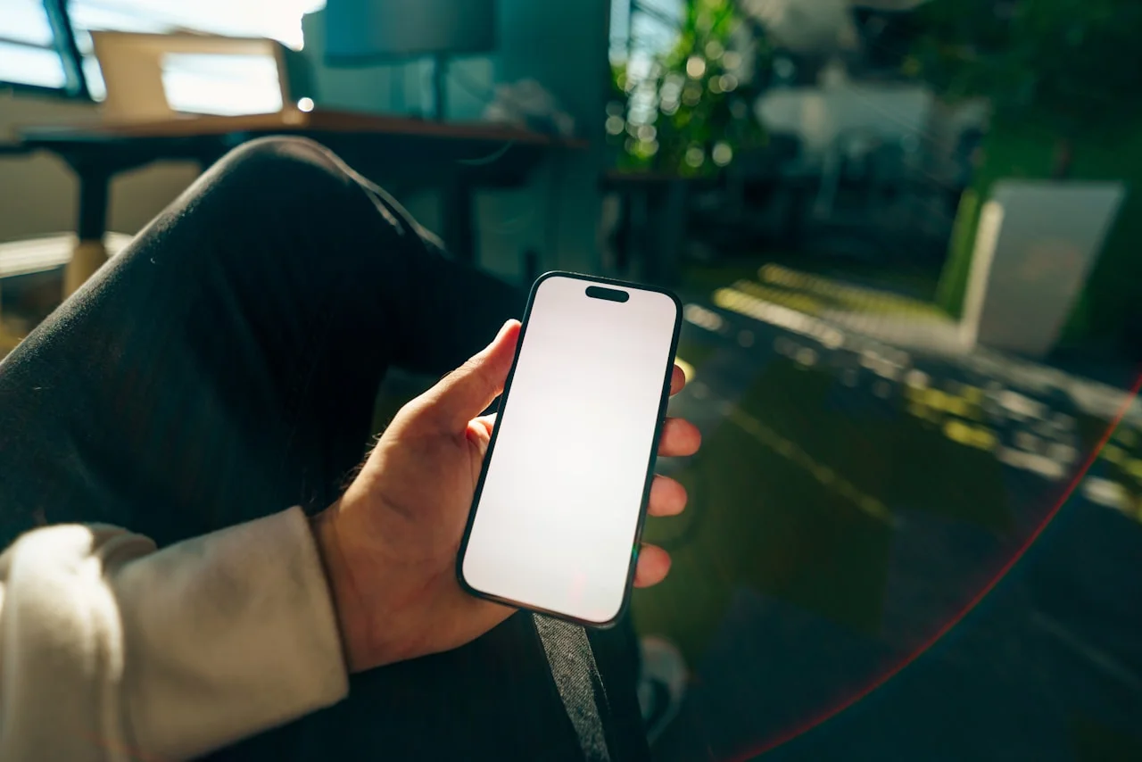 Ruka drži mobitel s vrlo svijetlim zaslonom pri dnevnom svjetlu
