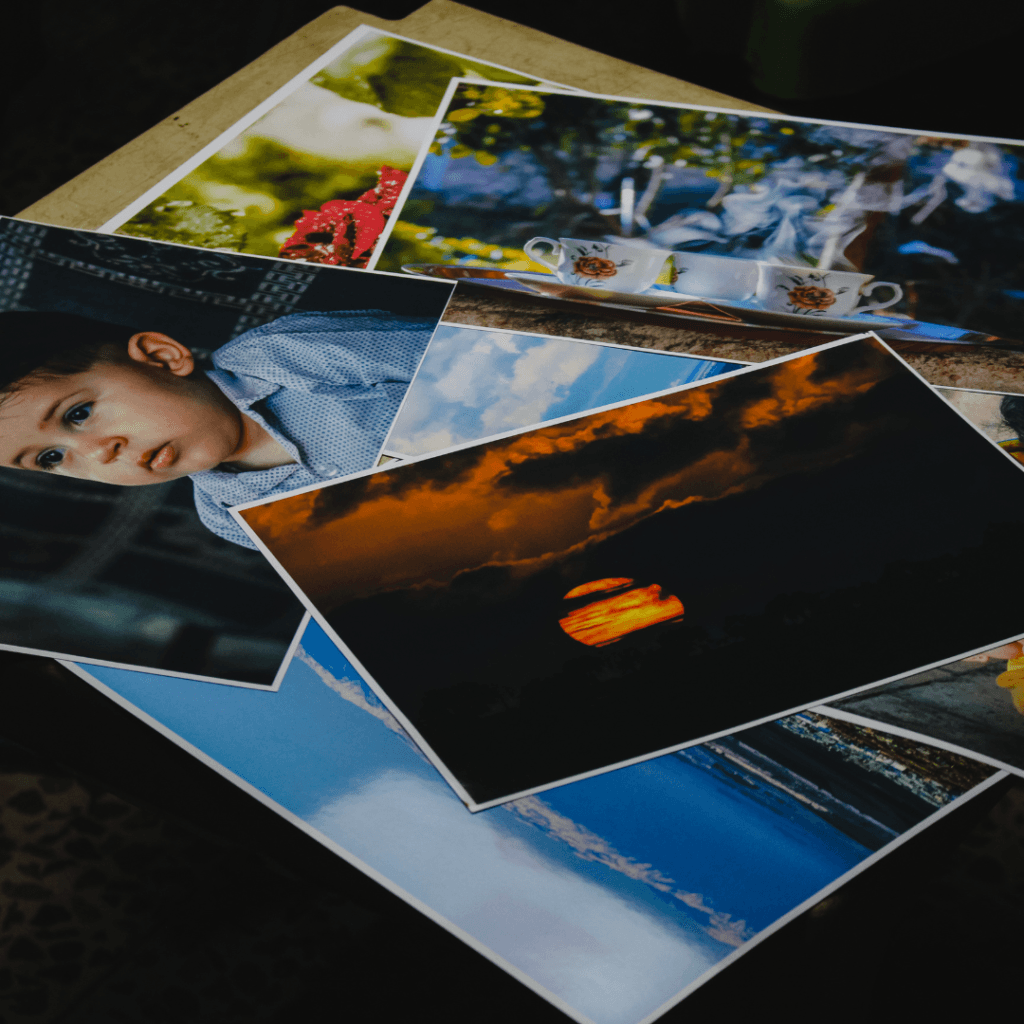 Kolekcija različnih natisnjenih fotografij razporejenih po temni površini - portreti, pokrajine in vsakdanji motivi